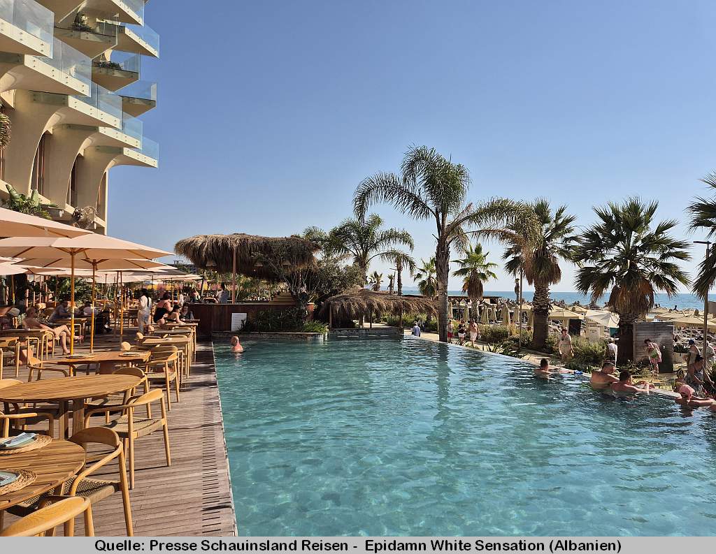 Blick auf den Pool des Epidamn White Sensation. Links befinden sich Tische und Stühle - rechts sind Palmen, der Strand sowie das Meer sichtbar.